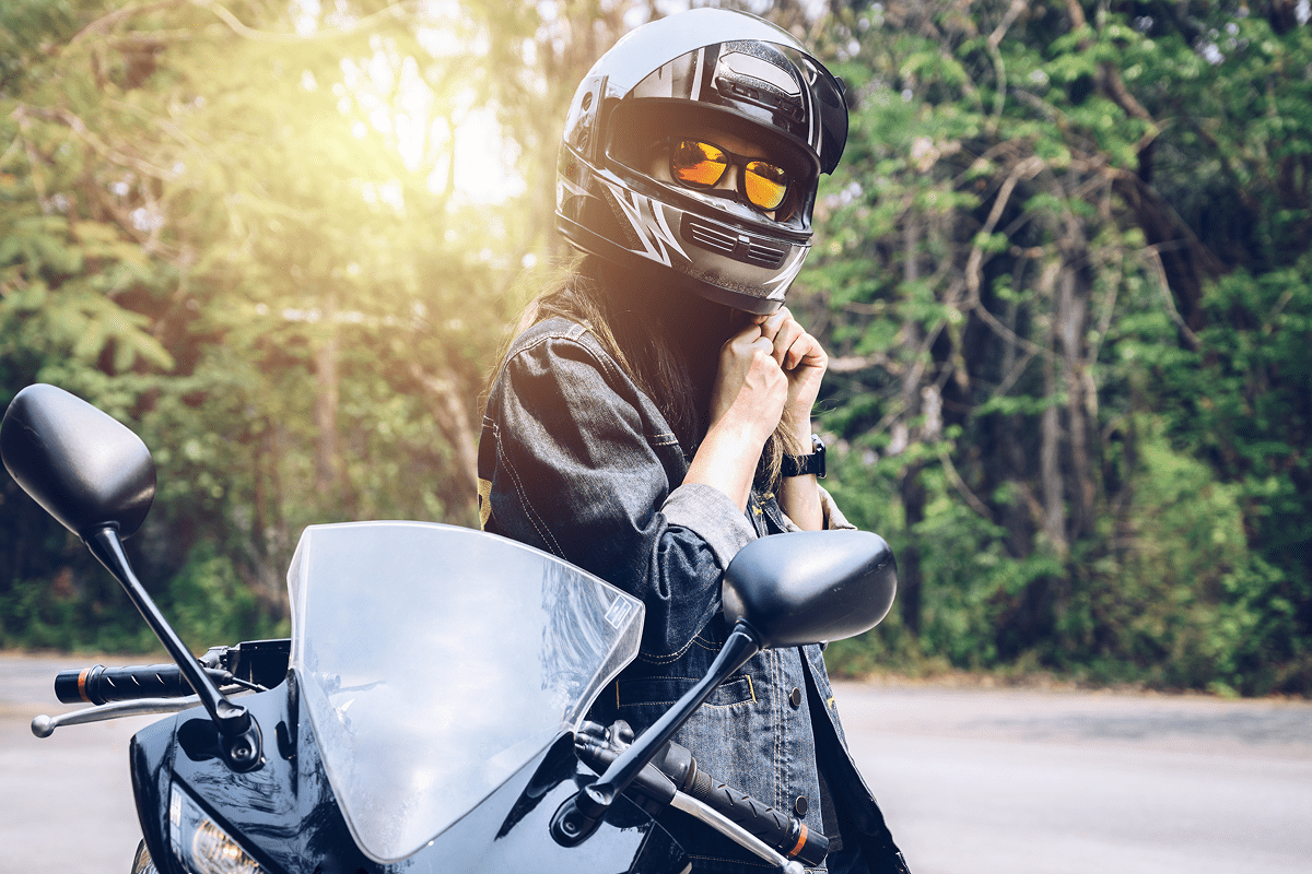 Person in helmet beside black motorcycle outdoors.