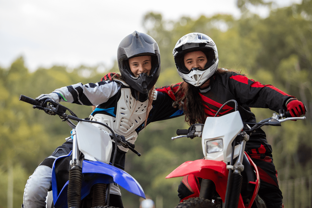 Two motorcyclists posing on dirt bikes.