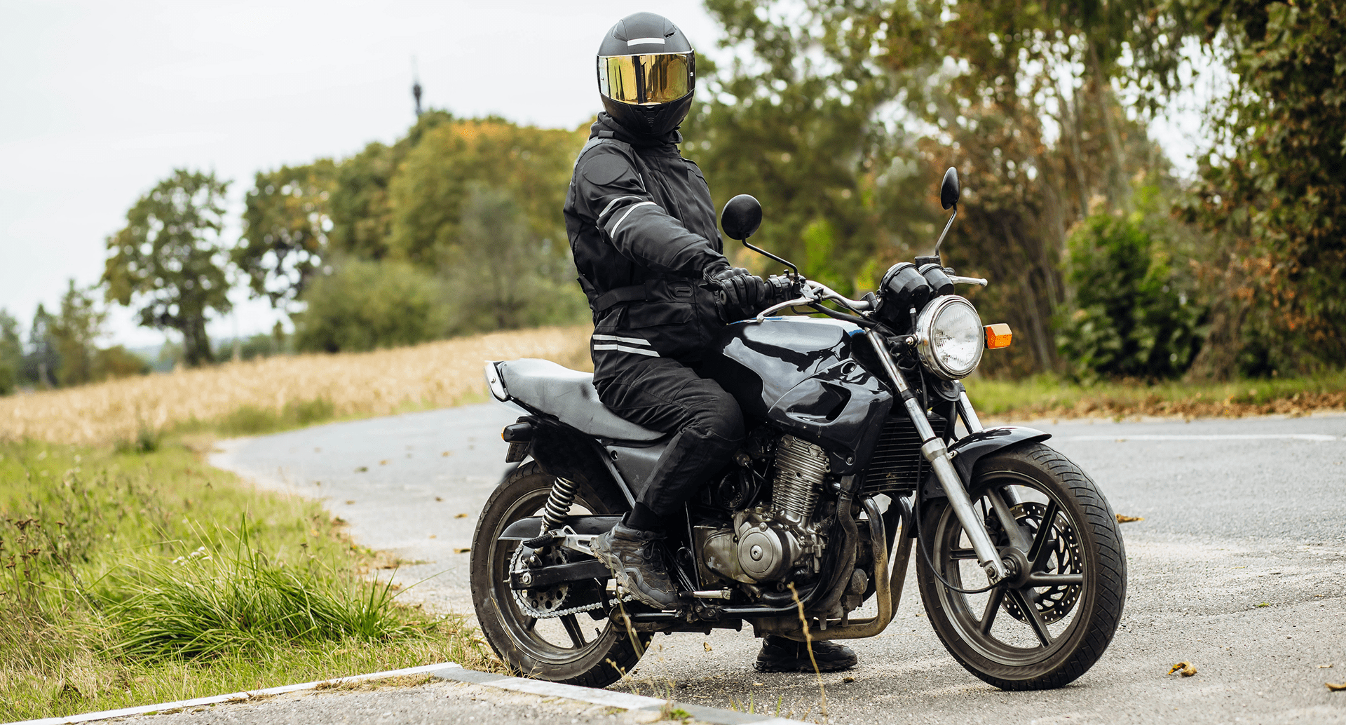 Motorcyclist in black gear on road.